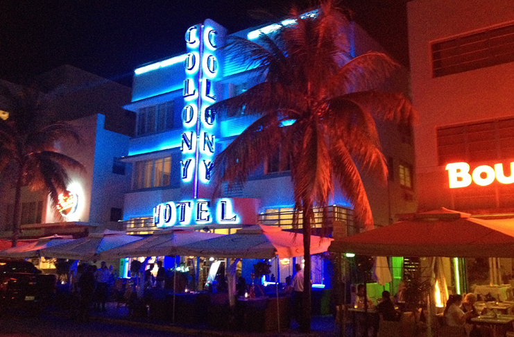 a building with neon lights and palm trees