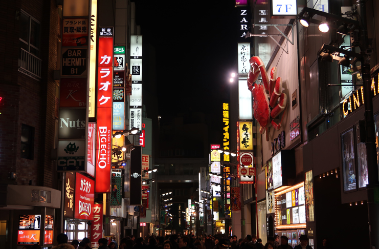 a street with signs and people walking around with Kabukichō, Tokyo in the background