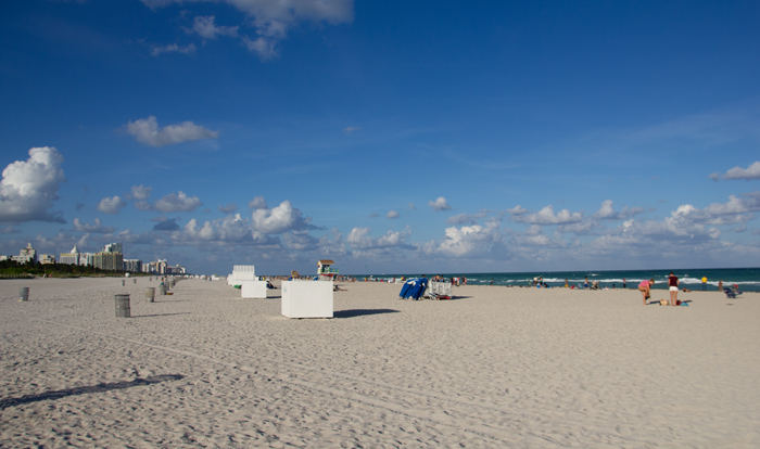a beach with many white boxes and blue chairs