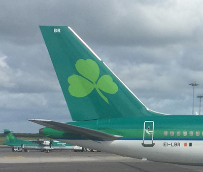 a green tail of an airplane with a clover on it