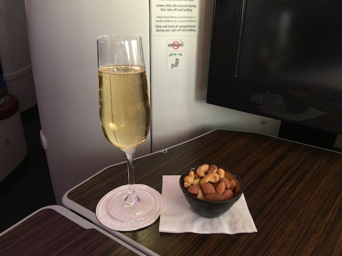 a glass of champagne and a bowl of nuts on a table