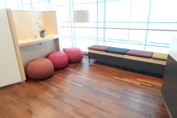 a room with a bench and pink poufs