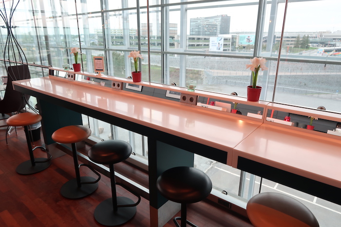 a long white counter with stools and flowers in pots