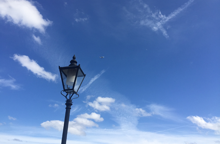 a lamp post with a plane flying in the sky