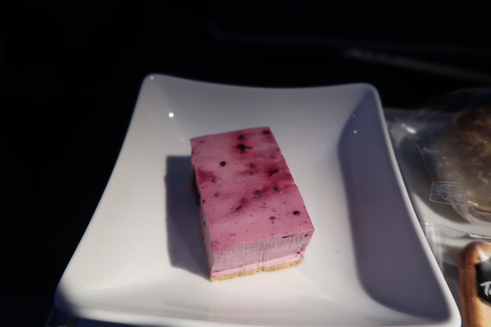 a square white plate with a pink dessert on it