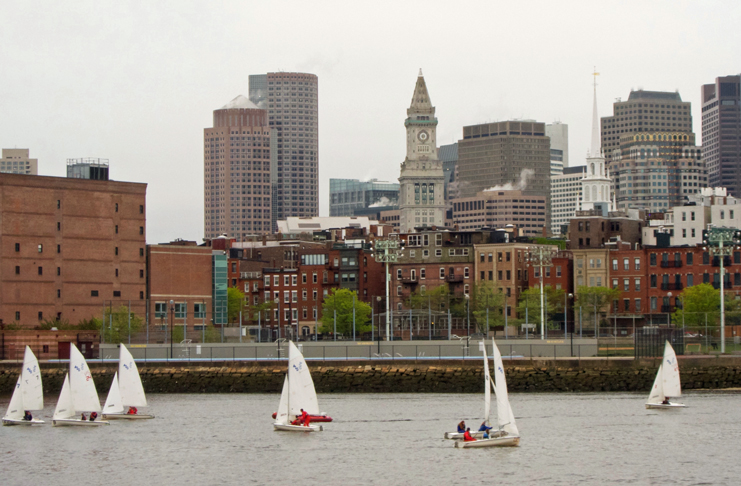 a group of sailboats in a body of water with a city in the background