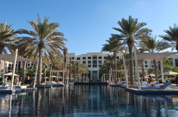 a pool with palm trees and a building with a large building