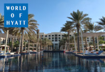 a pool with palm trees and a building with a white building