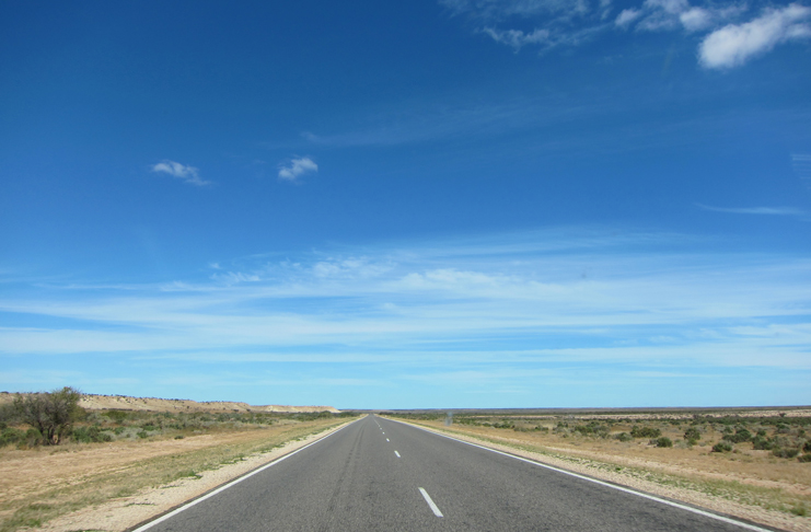 a road with a blue sky and clouds