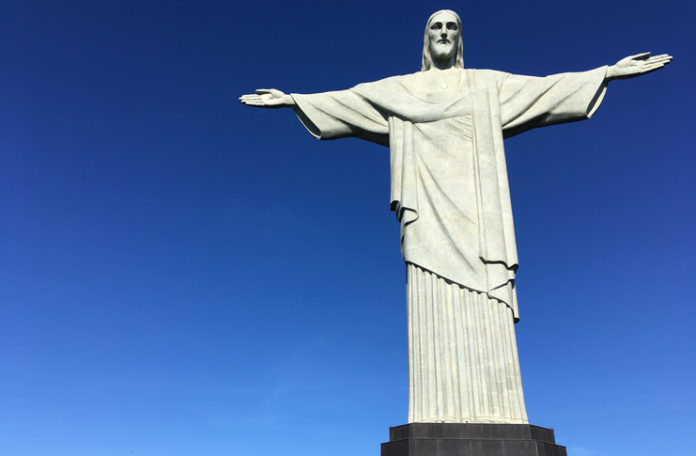 a statue of a man with his arms out with Christ the Redeemer in the background