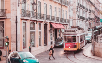 a woman walking on a street with cars and a trolley