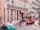 a woman walking on a street with cars and a trolley