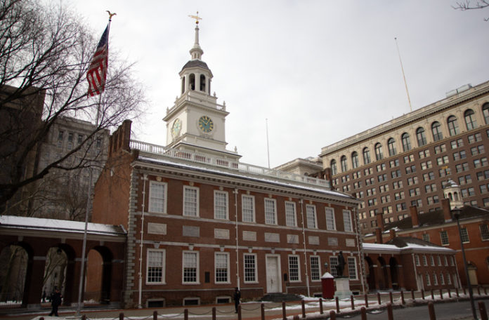 Independence Hall with a clock tower and flags