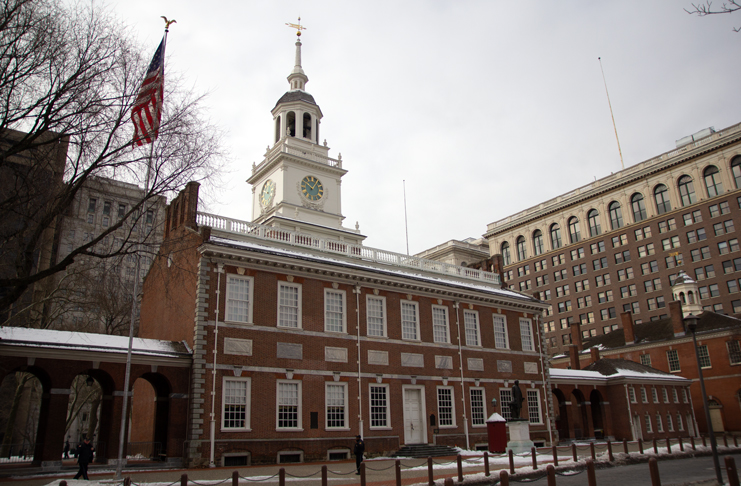 Independence Hall with a clock tower and flags