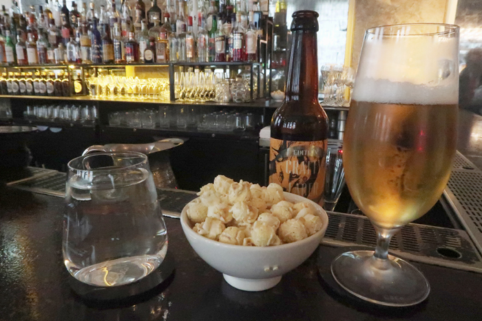 a bowl of popcorn and a beer on a bar counter