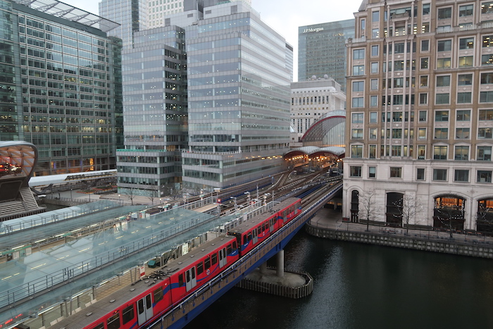 a train going over a bridge over a river with buildings in the background