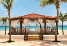 a gazebo with white curtains and a beach view