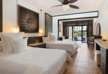 a room with two beds and a ceiling fan