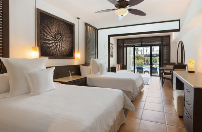 a room with two beds and a ceiling fan