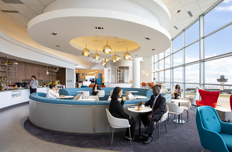 people sitting at tables in a room with large windows