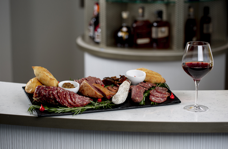 a plate of meat and bread with a glass of wine