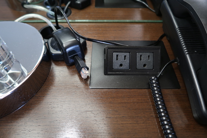 a black electrical outlet with wires on a wood surface