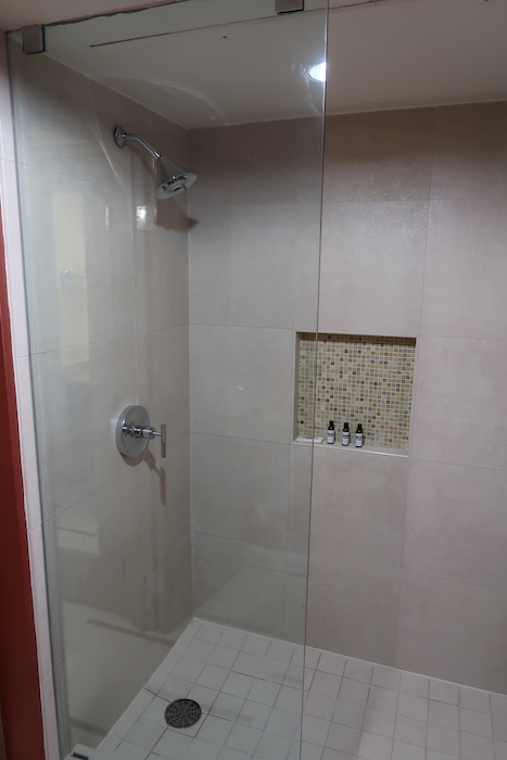 a shower with a tile wall and a shower head