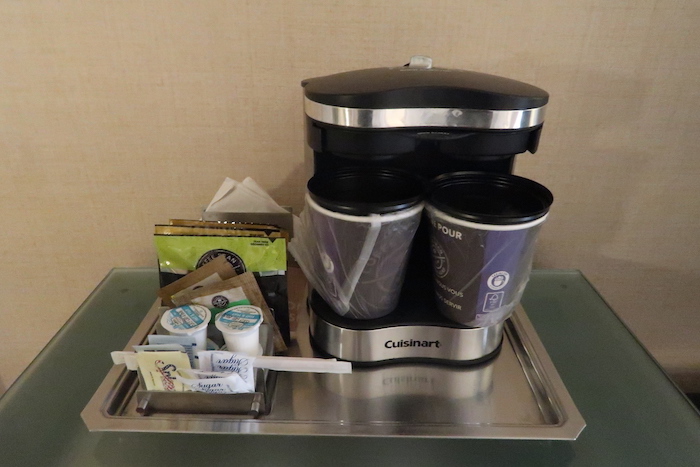 a coffee maker with cups and other items on a tray