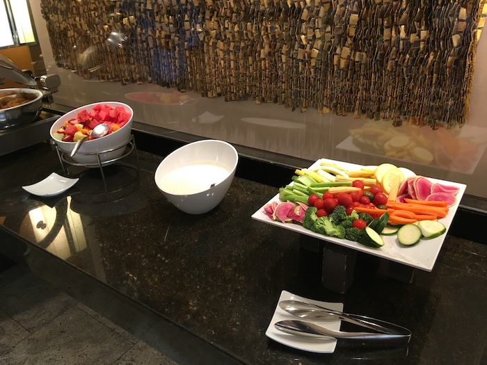 a buffet table with bowls of food and spoons