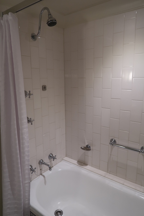 a bathtub and shower with white tile walls