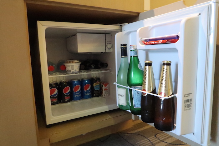 a mini fridge with bottles of beer and soda