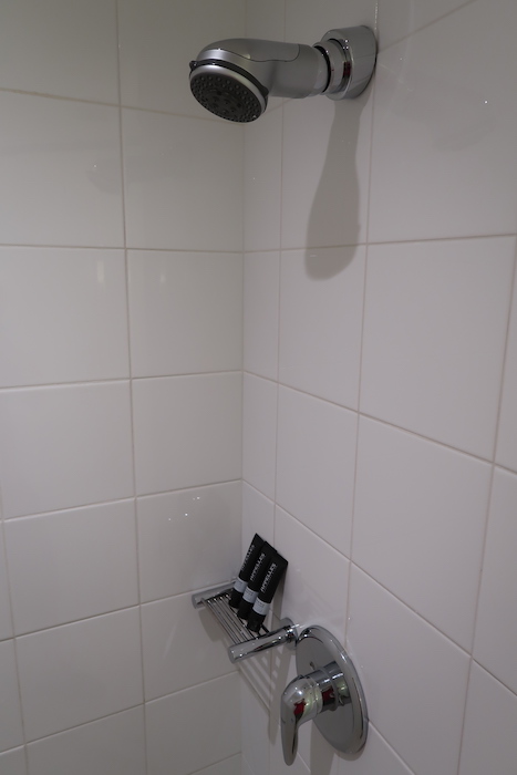 a shower with white tile walls