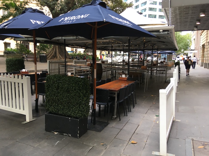 tables and chairs under umbrellas on a sidewalk