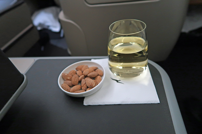 a bowl of almonds and a glass of liquid on a tray