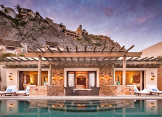 a pool with a building and a hill in the background
