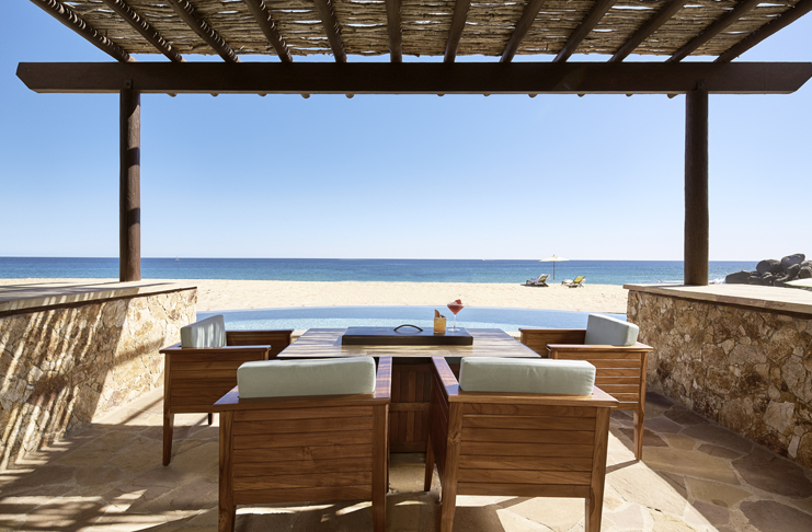 a table and chairs on a patio overlooking a beach