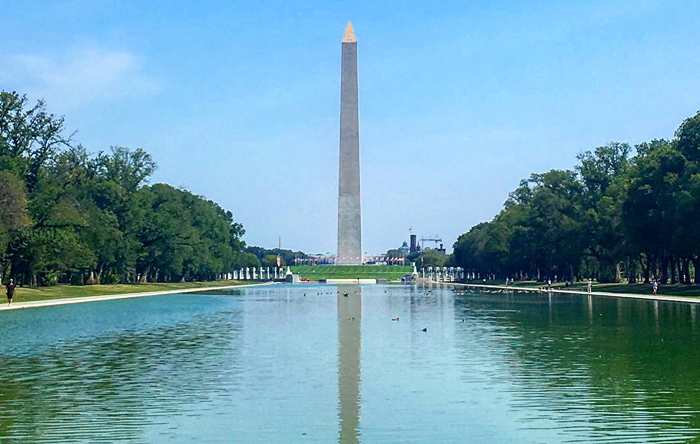 a large monument with a body of water with Washington Monument in the background