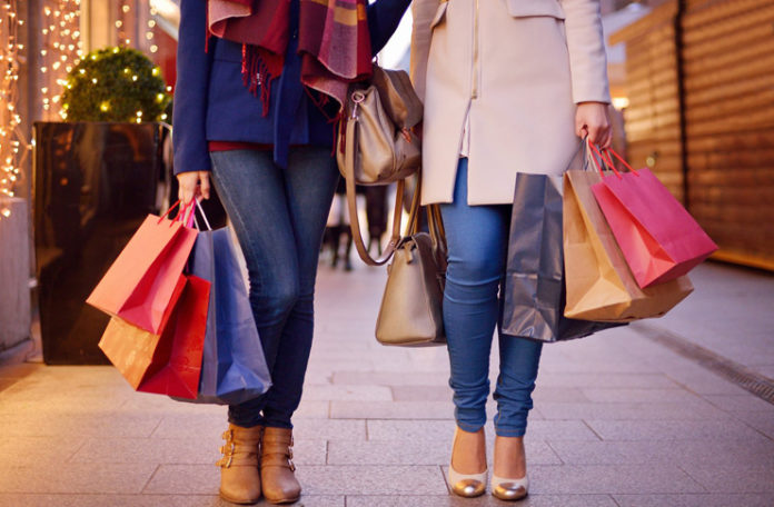 a pair of women holding shopping bags