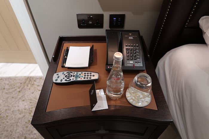 a hotel room table with remote control and phone