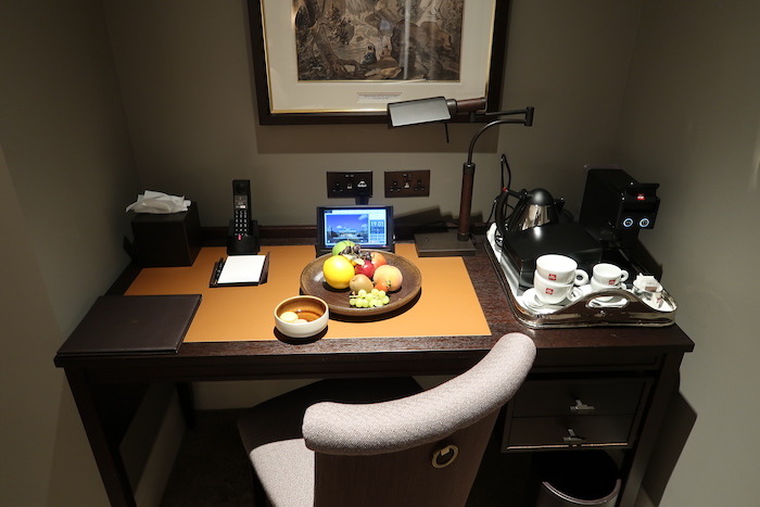 a desk with a bowl of fruit and a laptop