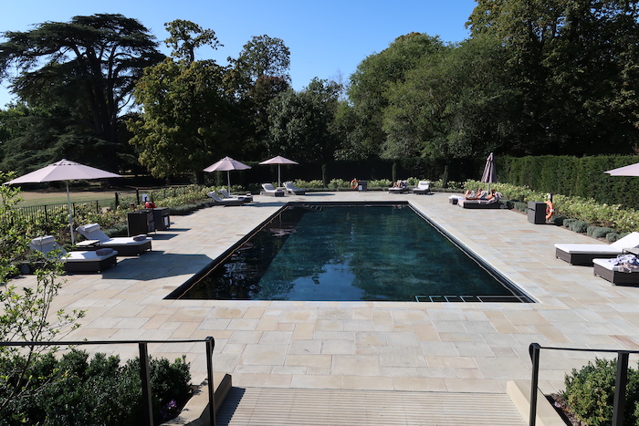 a pool with people sitting on chairs and umbrellas