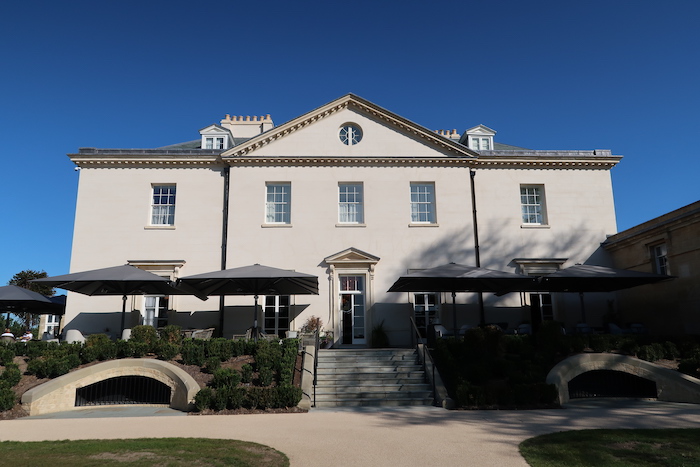 a large white building with a walkway and umbrellas