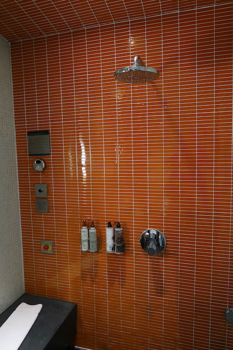 a shower with orange tile walls