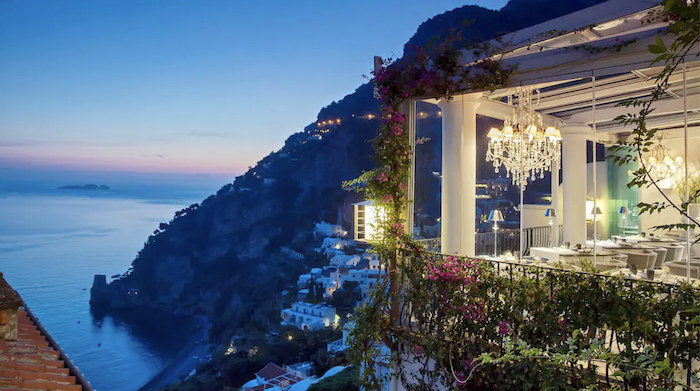 a building with a chandelier and flowers on the side of a cliff