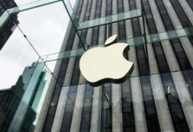 a large white apple sign on a glass building