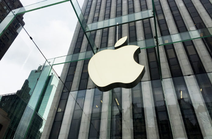a large white apple sign on a glass building