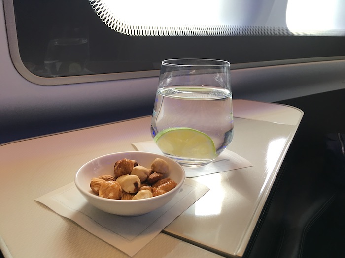a bowl of nuts and a glass of water on a table