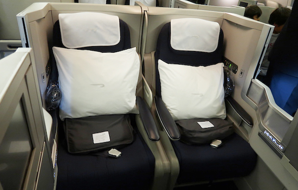 two seats with white pillows and a cell phone on them