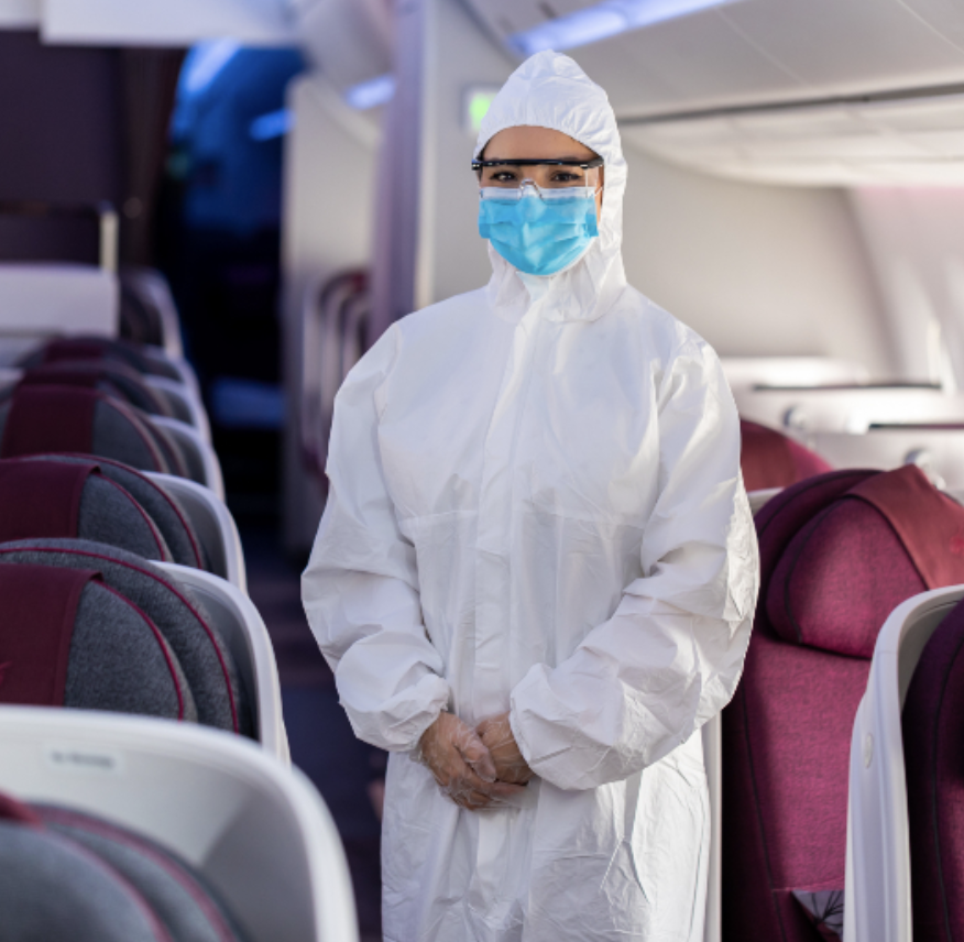 a person in a white protective suit and mask standing in an airplane