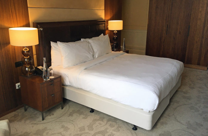 a bed with white sheets and a wooden headboard